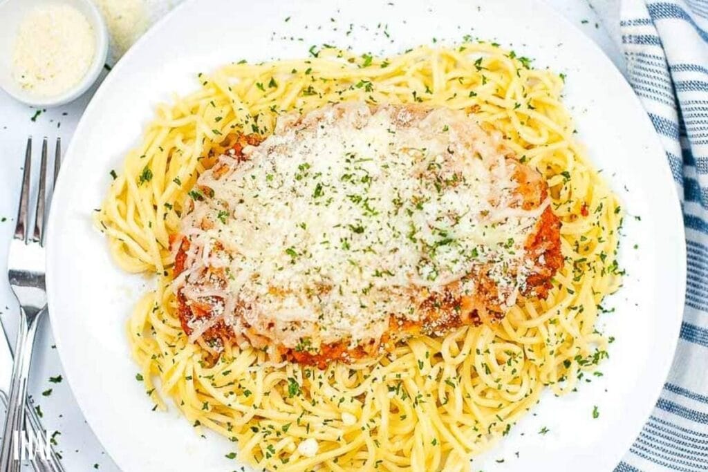 top shot of air fried chicken parm on spaghetti noodles garnished with parsley