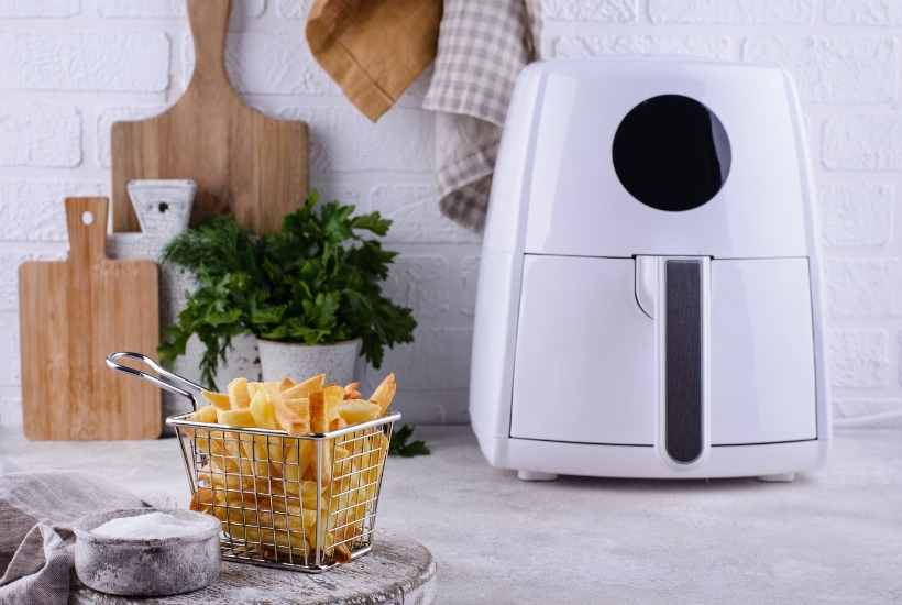 white air fryer sitting next to a basket of fries